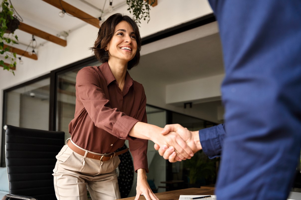 Handshake of happy young business woman and business man